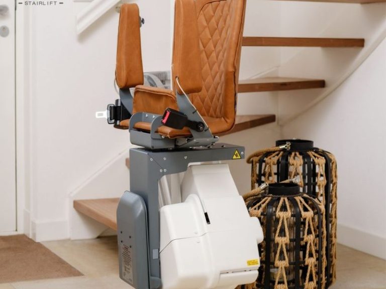 Treppenlift mit braunem Sitz und beige-weißer Basis vor einer Treppe. Treppenlift mit braunem Sitz und beige-weißer Basis vor einer Treppe.